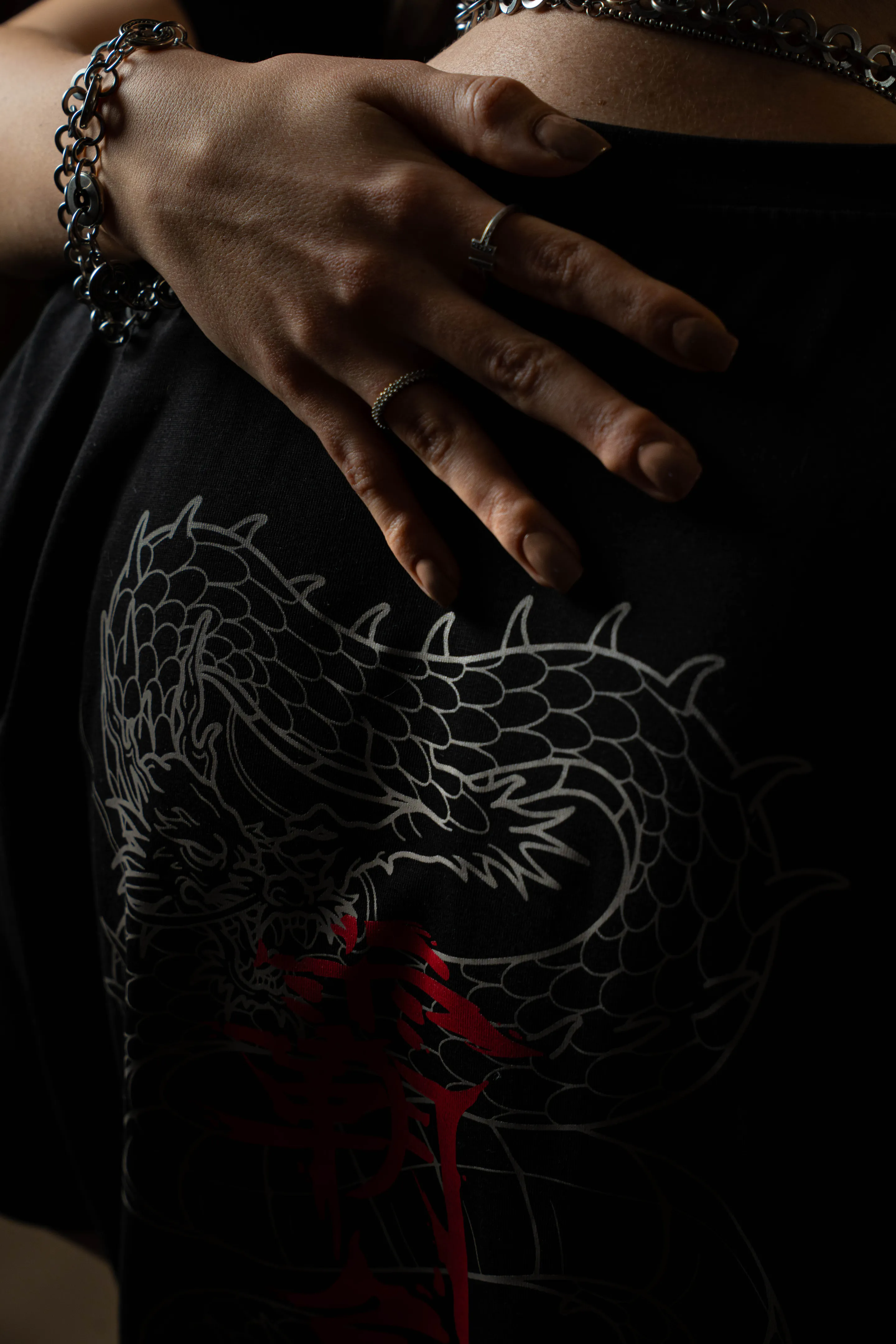 A hand with silver rings resting over the dark dragon back print