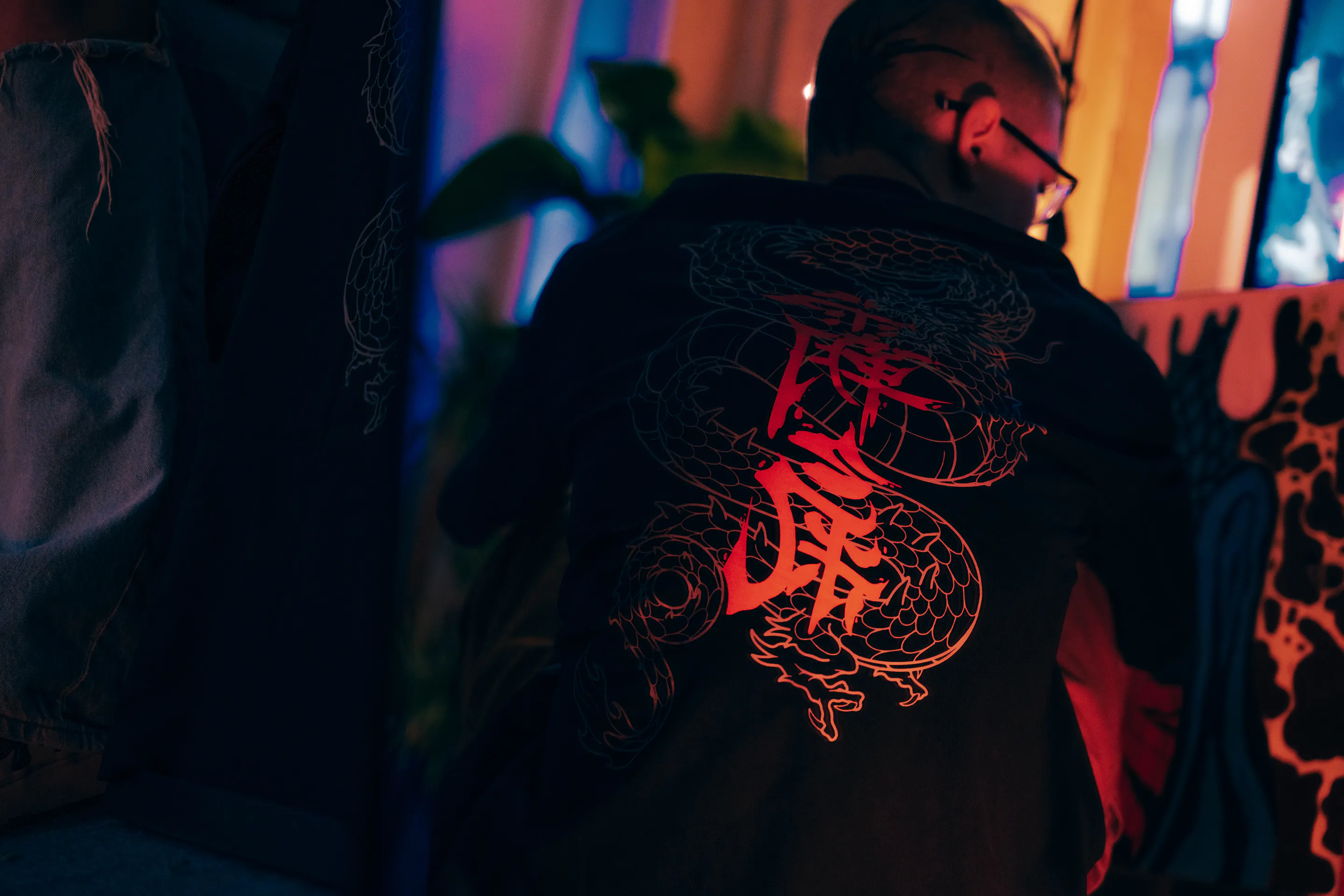 The back print burning red under red light, cigarette smoke at the window