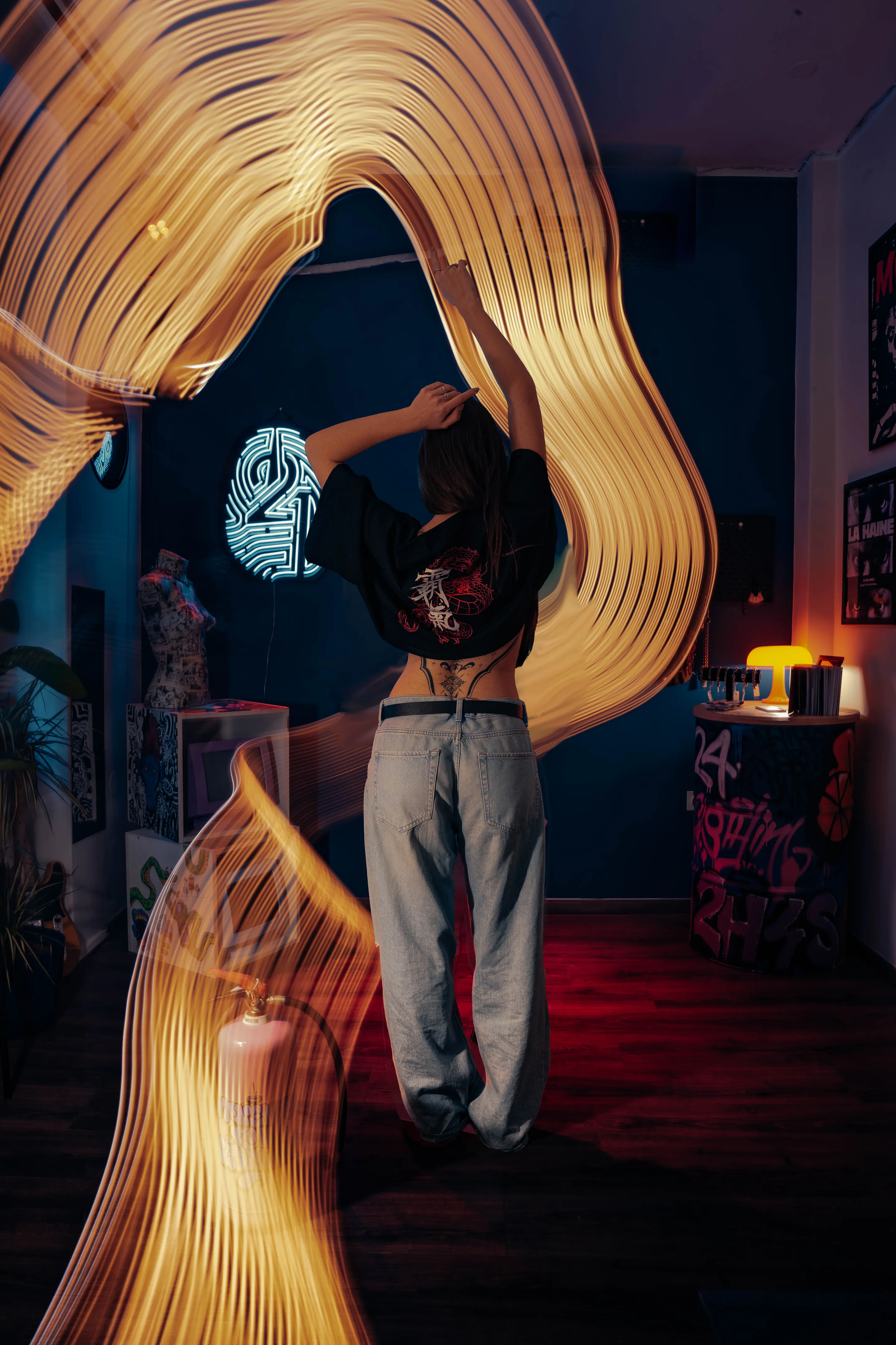 Long-exposure ribbons of light wrapping her as she lifts the tee