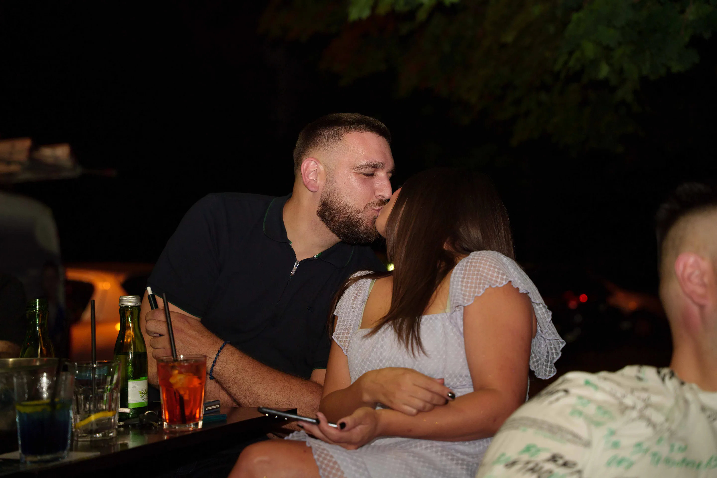 A kiss at the bar, cocktails untouched