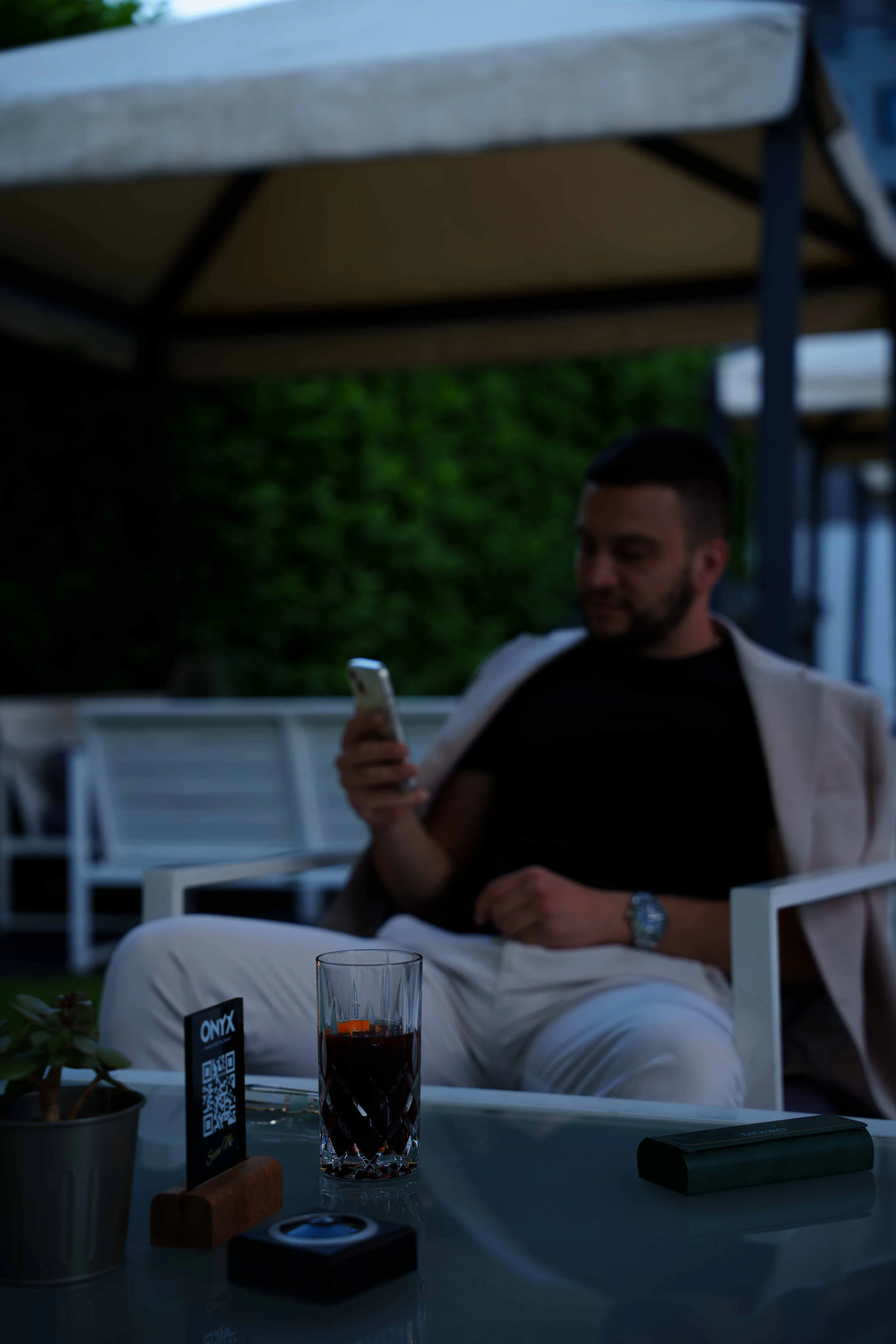 The table at dusk — iced drinks, an ashtray, a lit phone