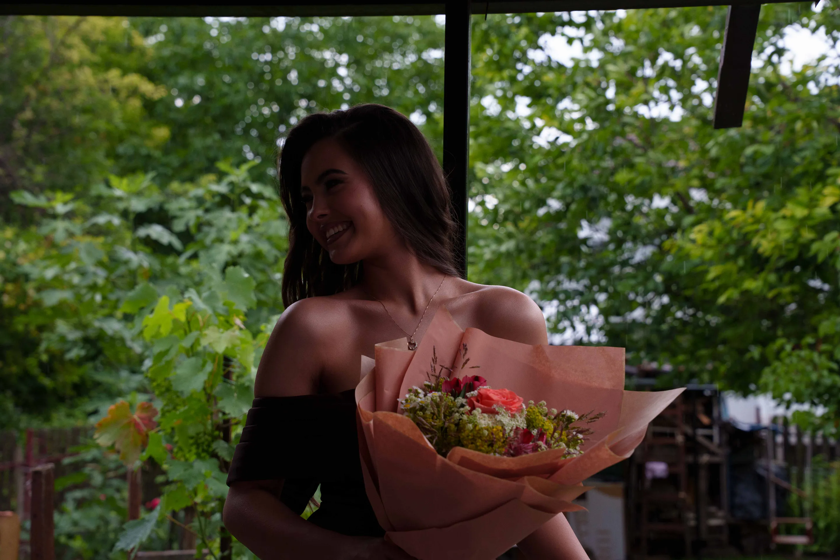 Portrait in low light, the bouquet at her shoulder