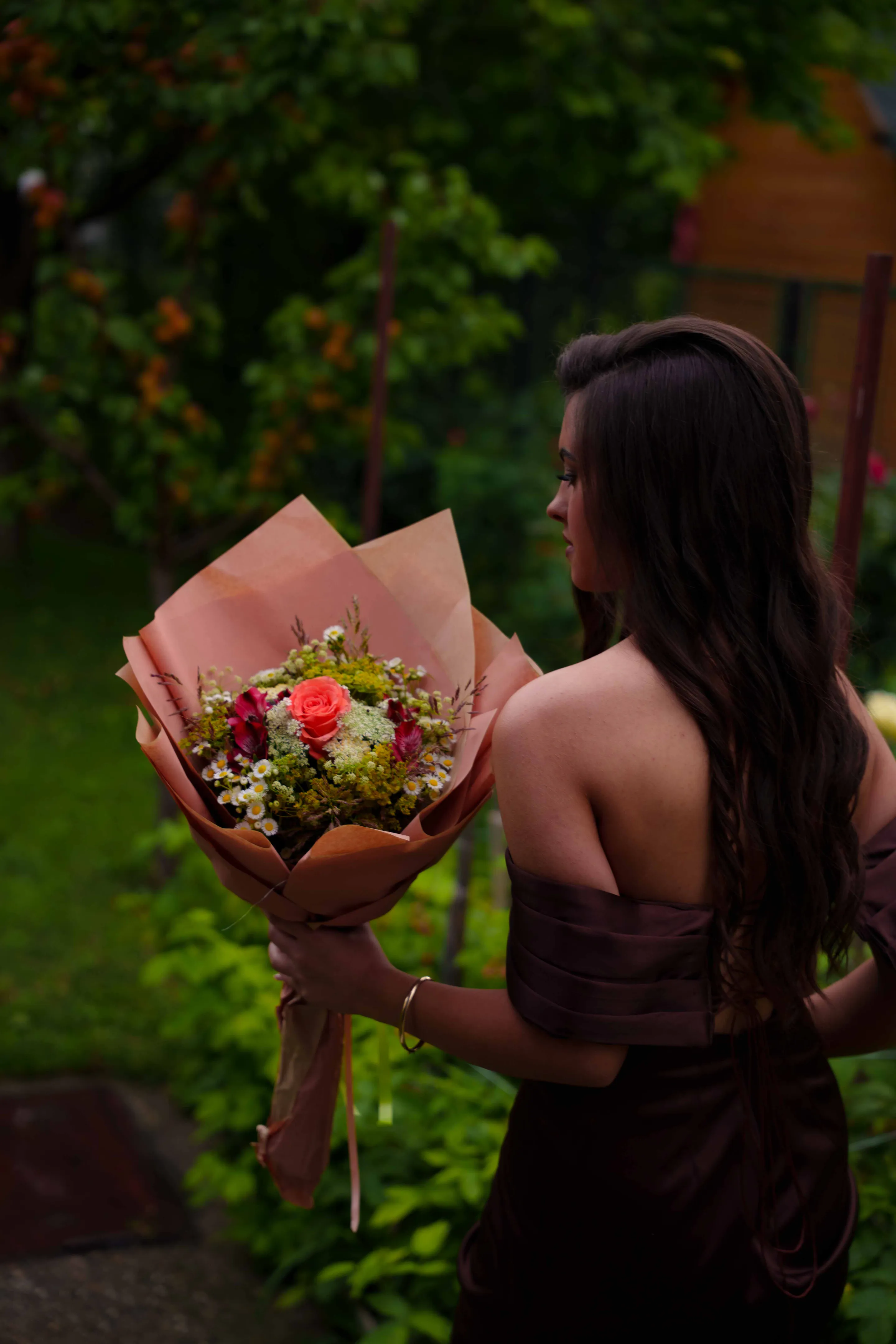 The bouquet held close in its paper wrap, red against cream