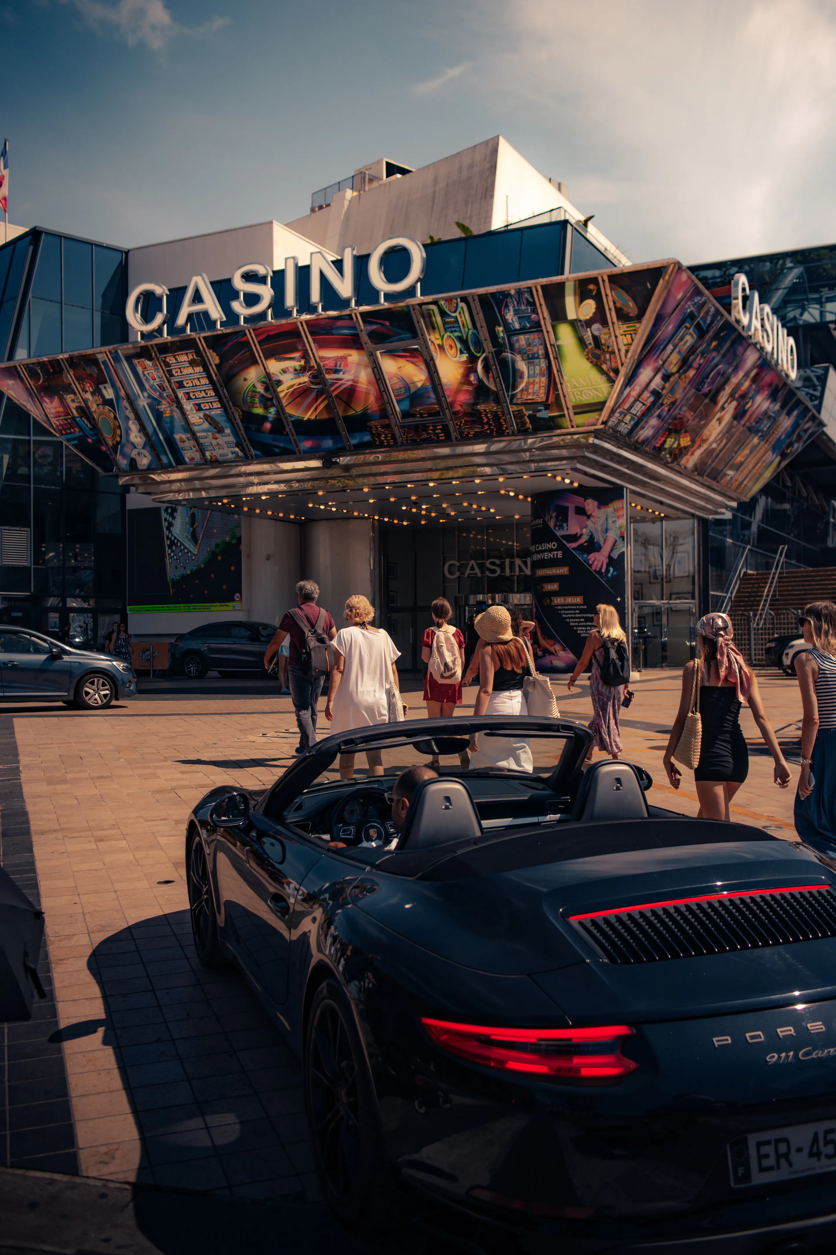 Black 911 cabriolet in the casino plaza, pedestrians under the marquee
