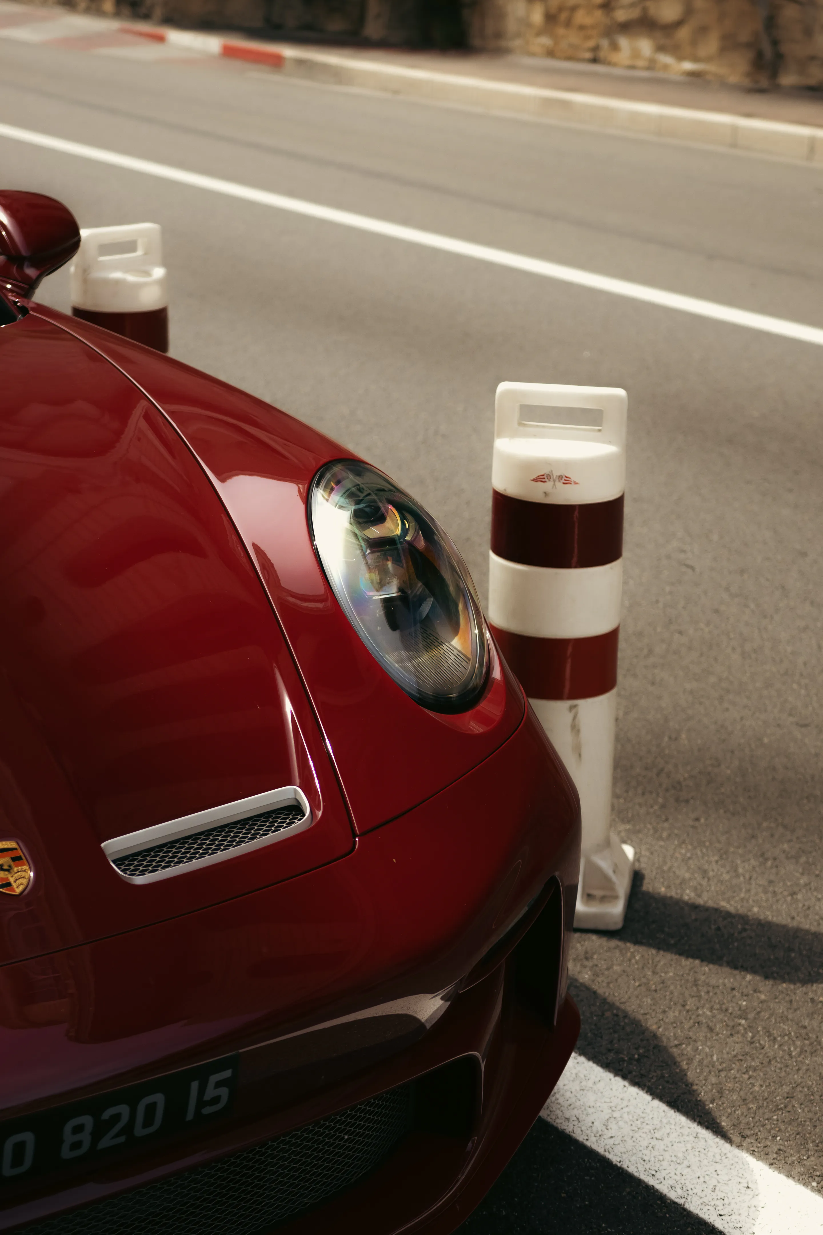 Top-down on the red fender and round headlight beside a striped bollard