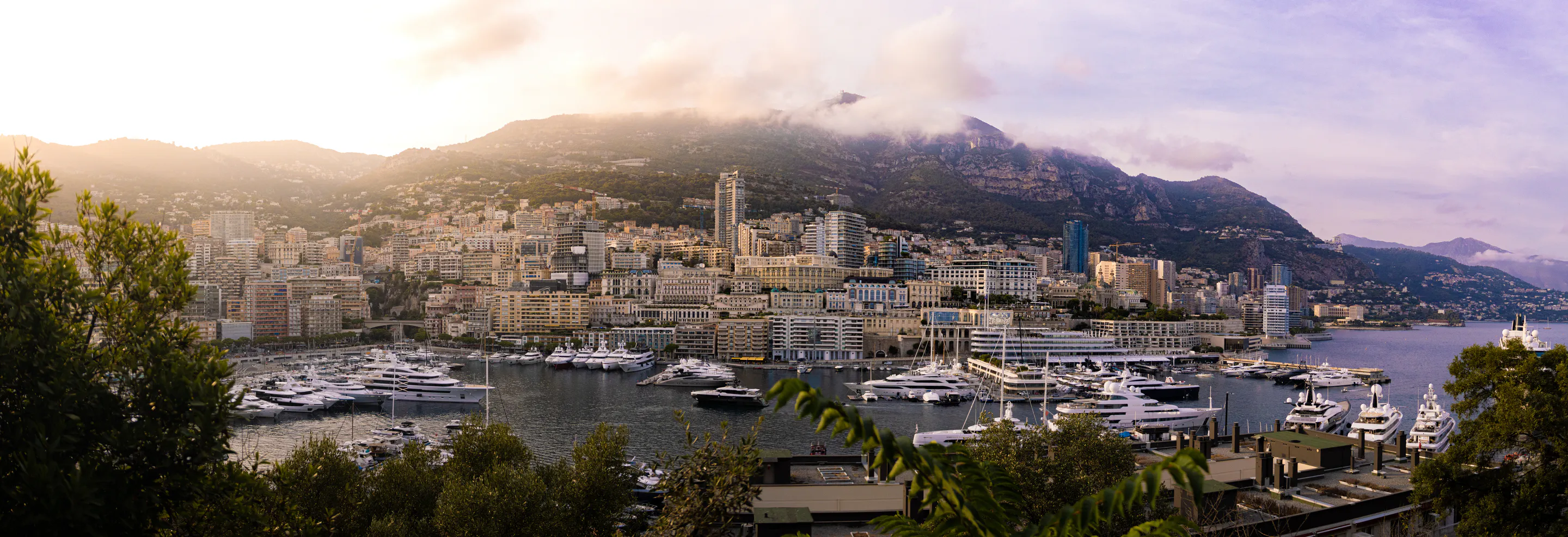 Wide sweep of the marina fronting the hillside city, mist on the ridge