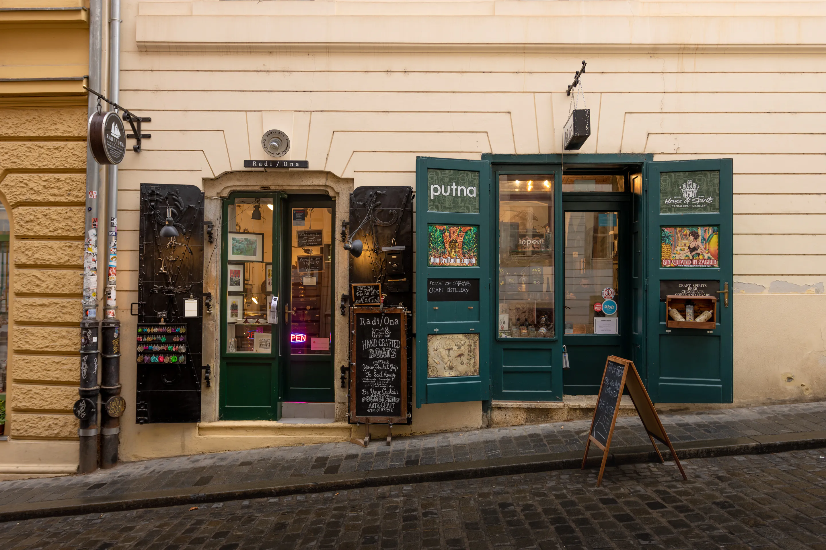 A flat row of shopfronts — teal shutters and hand-painted signage
